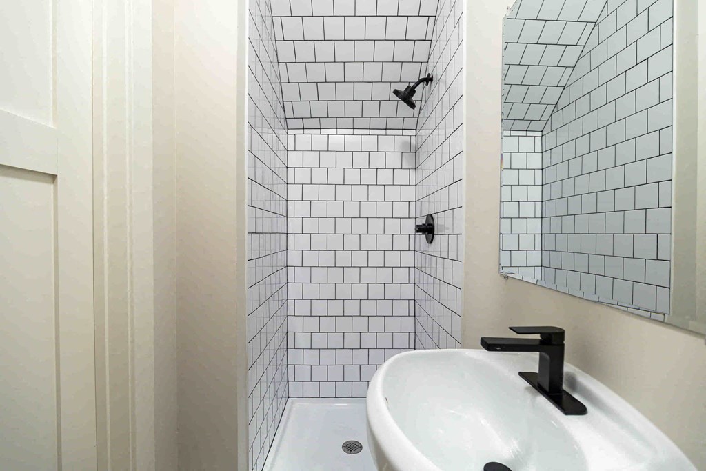 a white tiled bathroom with a sink and a shower