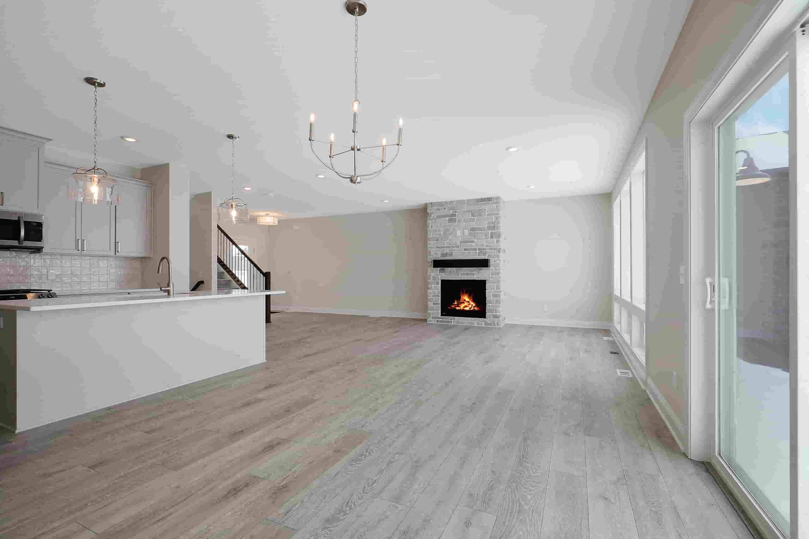 an empty living room with a fireplace and a kitchen