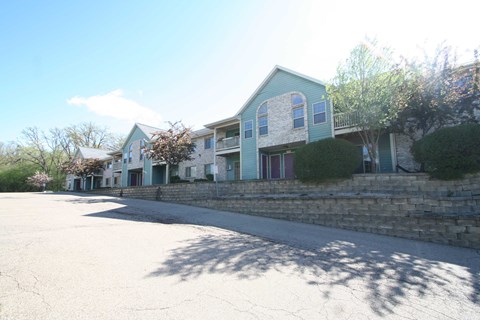A large building with a blue and white exterior is surrounded by a stone wall and a tree.