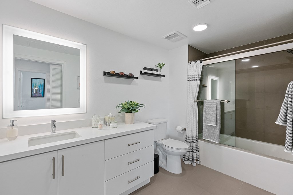 a white bathroom with a large mirror and a shower and a toilet