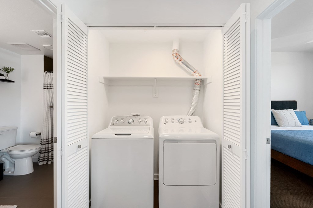 a washer and dryer in a room with a bed and a toilet