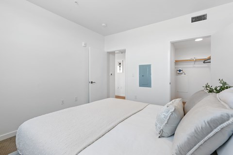 A white bedroom with a large bed and a mirror on the wall.