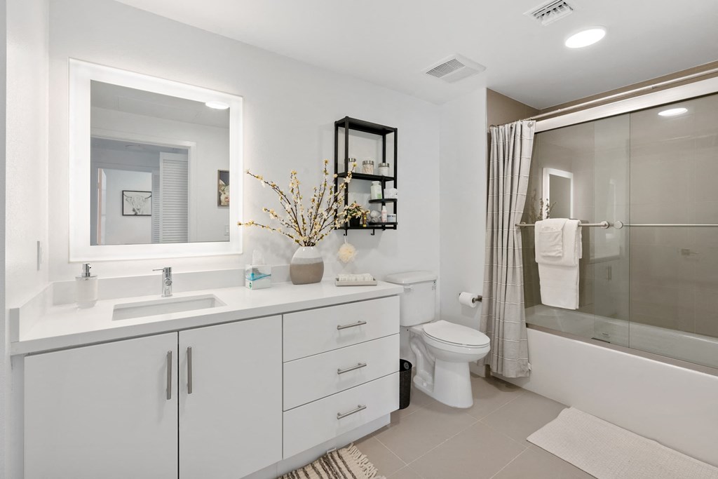 a white bathroom with a large mirror and a shower