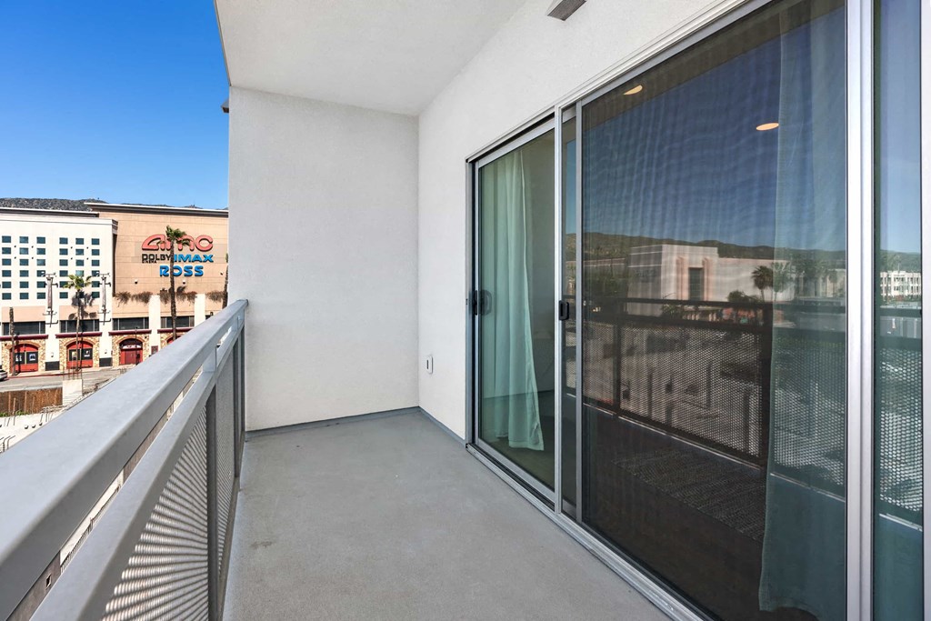 a balcony with a glass door and a view of the city