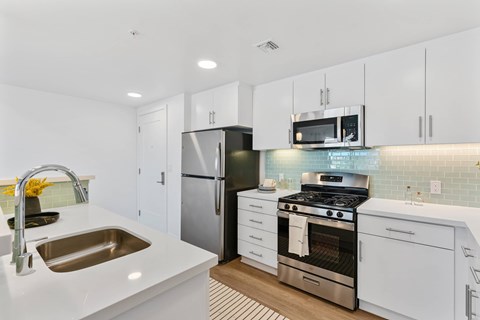 A modern kitchen with white cabinets and stainless steel appliances.
