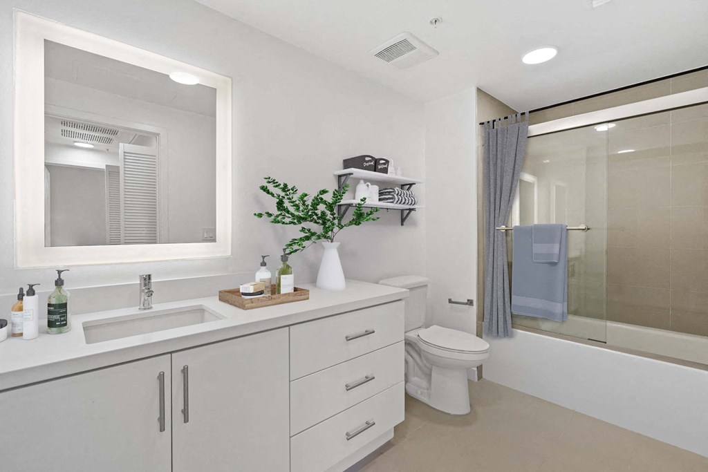 a white bathroom with a large mirror and a toilet