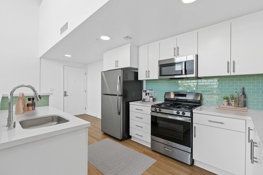 a white kitchen with stainless steel appliances and white cabinets