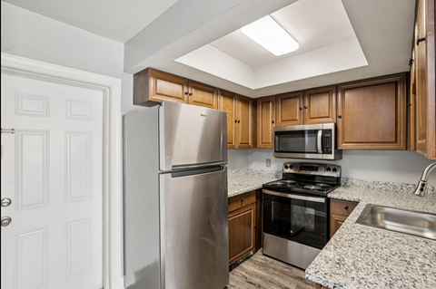 A kitchen with a refrigerator, microwave, oven, and sink.