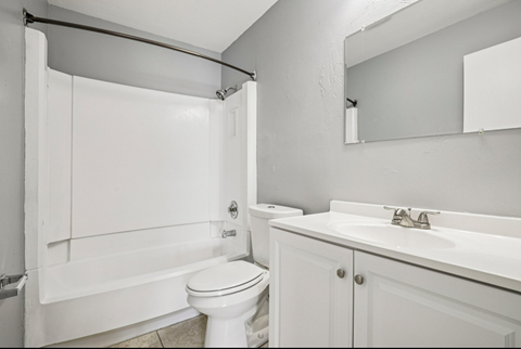 A white bathroom with a toilet, sink, and shower.