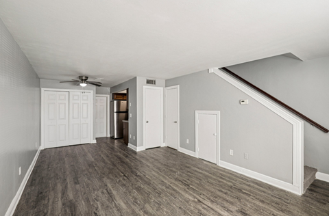 A room with a ceiling fan and wooden flooring.