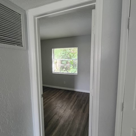 A room with a window and a wooden floor.