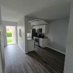 A kitchen with white cabinets and a black fridge.