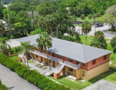 an aerial view of a yellow house with a gray roof and palm trees