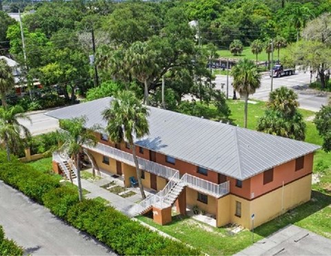 A building with a red roof and a balcony surrounded by greenery.