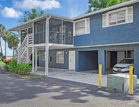 A blue two-story house with a white car parked in the driveway.