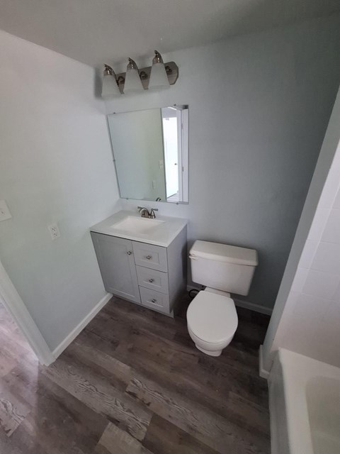 A white toilet sits in a bathroom next to a sink and mirror.
