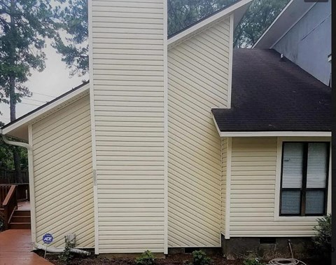 a yellow house with white siding on the side of it