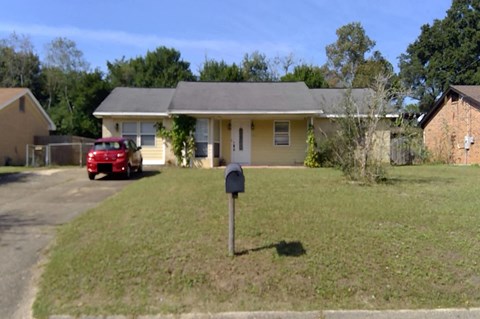 a house with a mailbox and a red car parked in the driveway