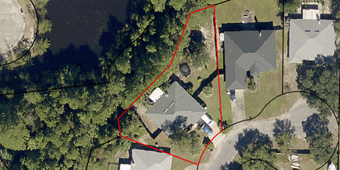 an aerial view of a house with a red boundary line around it and a tree