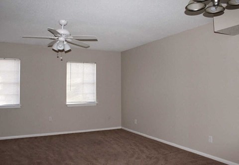A room with a ceiling fan and two windows.
