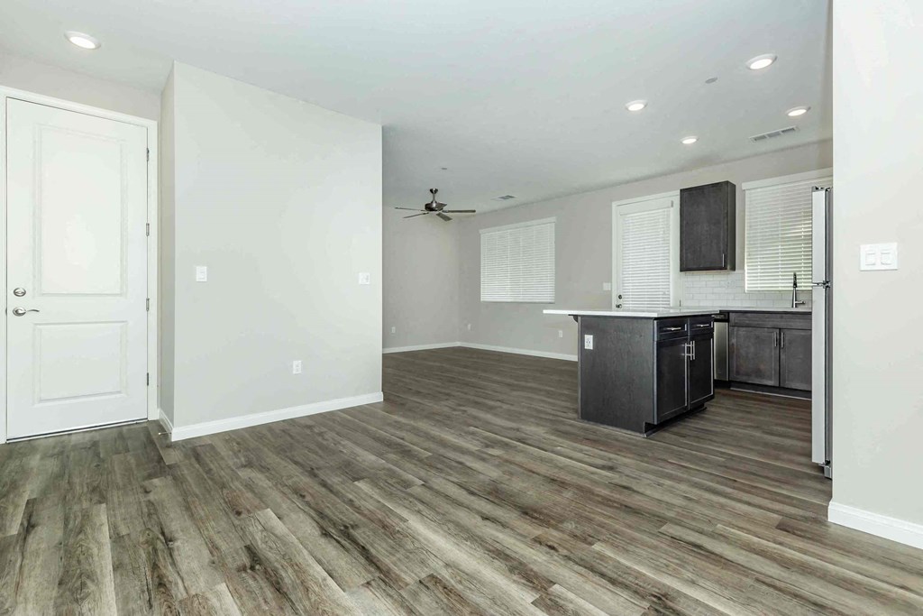 an empty living room with a kitchen and a door to a closet