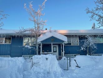 a blue house covered in snow on a clear day