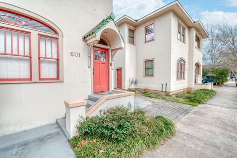 a white building with a red door and a sidewalk