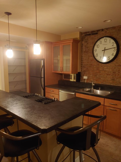 A kitchen with a black table and a brick wall clock.