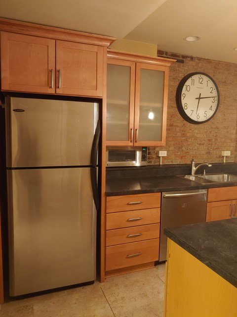 A kitchen with a stainless steel refrigerator and wooden cabinets.