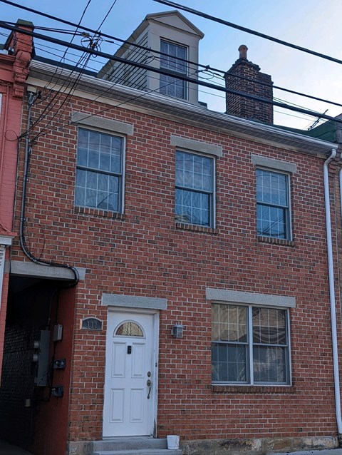 A red brick house with a white door and windows.