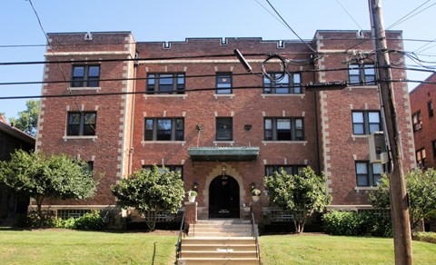 A large red brick building with a green lawn in front.