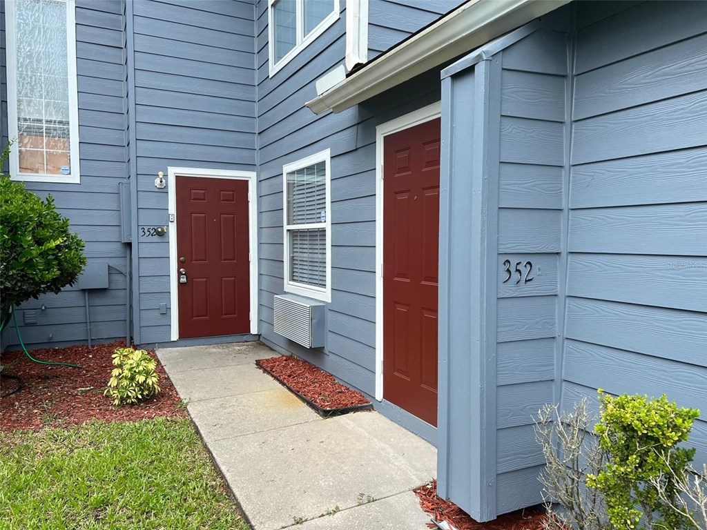 a blue house with two red doors and a sidewalk