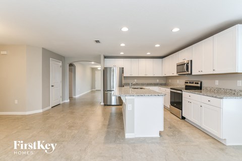 A kitchen with white cabinets and a granite countertop.