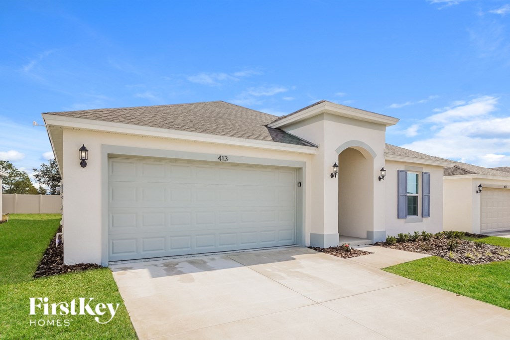 a beige house with a garage door and a lawn