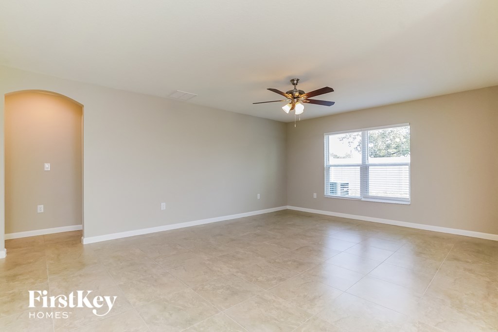 an empty living room with a ceiling fan and a window