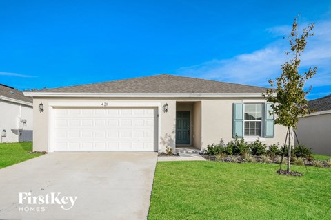 a beige house with a garage door and a lawn