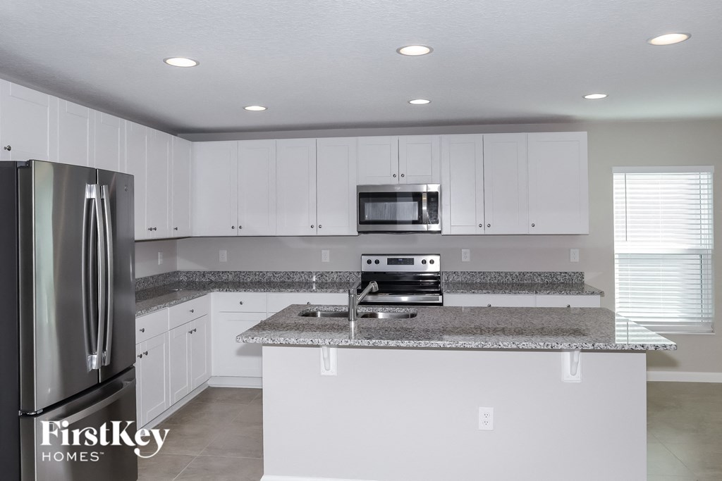 A kitchen with a stainless steel refrigerator and a granite countertop.