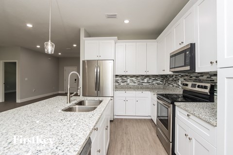 A kitchen with white cabinets and a granite countertop.