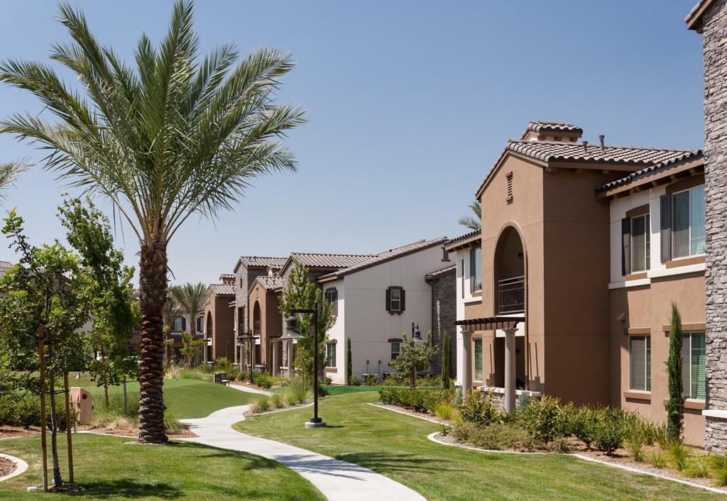 a group of apartment buildings with palm trees and grass