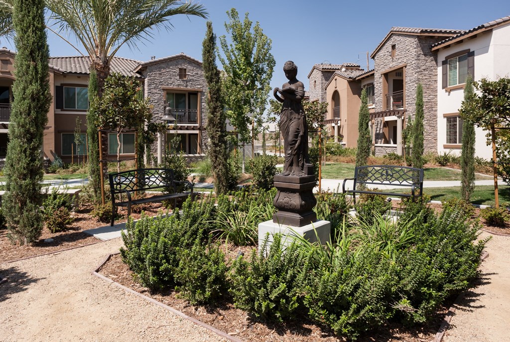 a statue of a woman in a garden in front of apartments