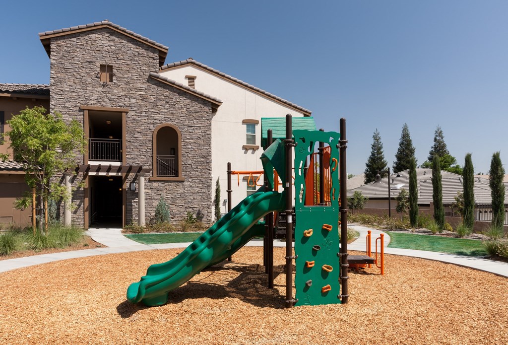 a playground in front of an apartment building with a green slide