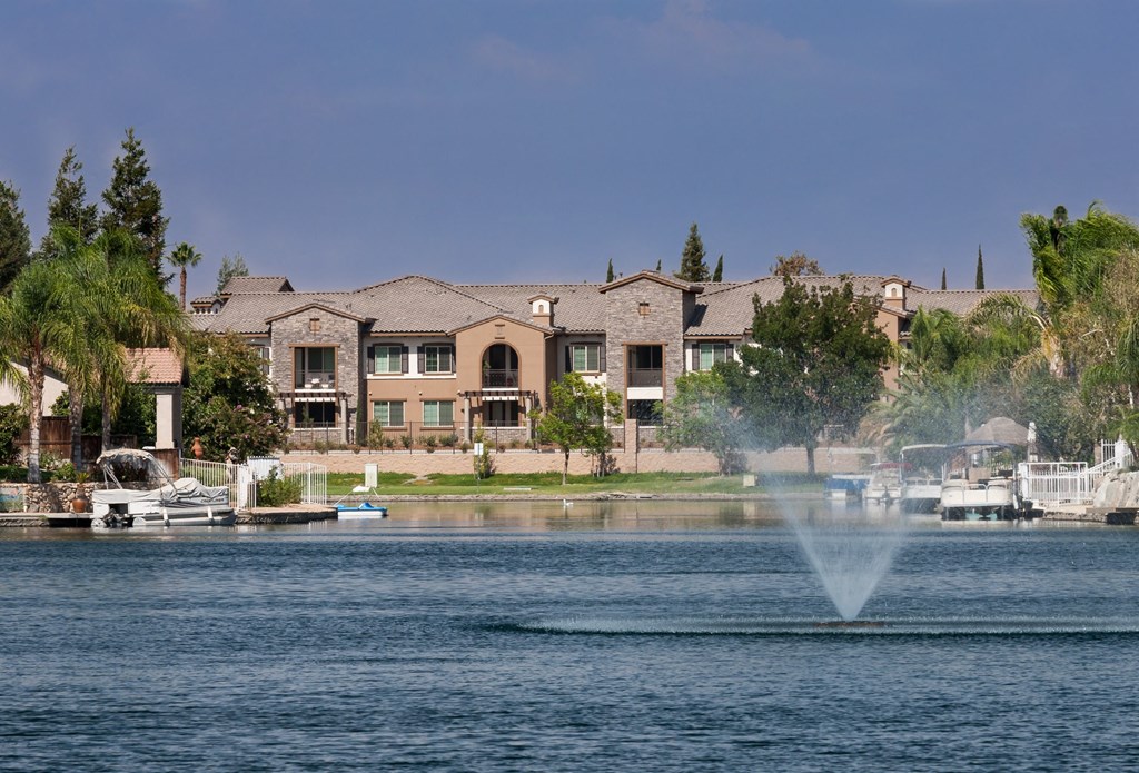 a fountain in the water at a lake with apartments in the background