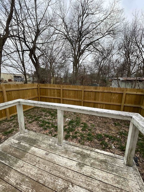 A wooden deck with a railing and trees in the background.