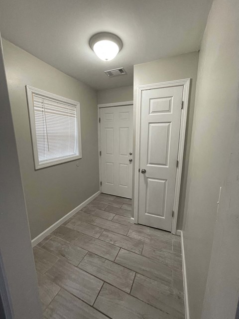 A hallway with a white door and a window with blinds.