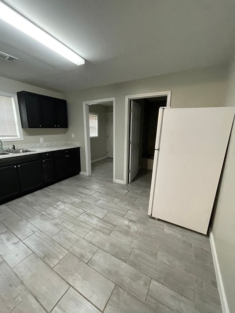 A kitchen with a white refrigerator and black cabinets.