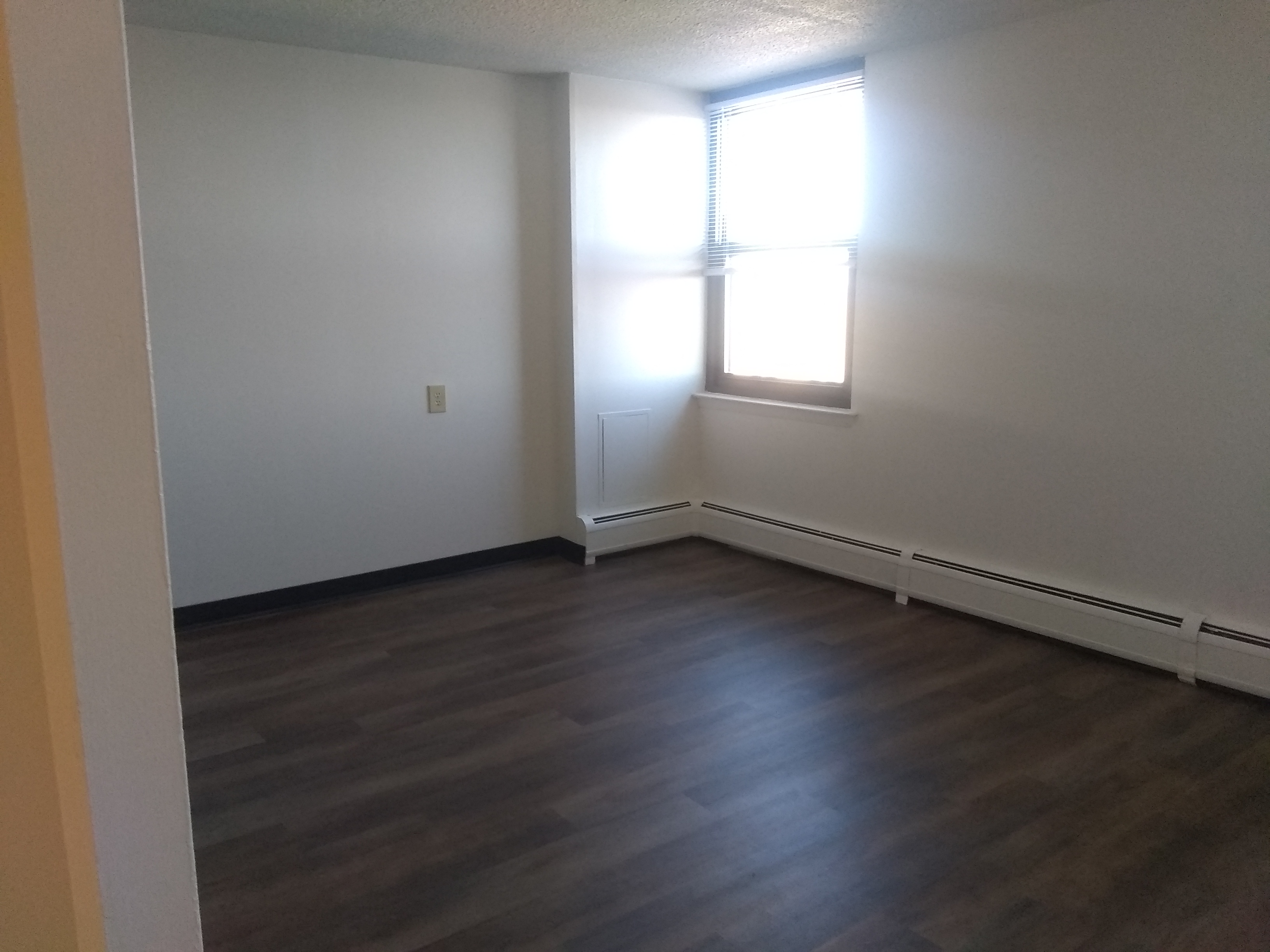 A room with a window and wooden flooring.