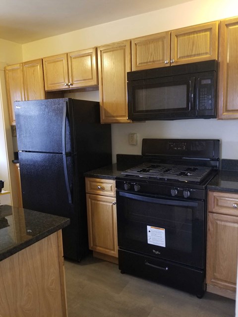 a kitchen with black appliances and wooden cabinets