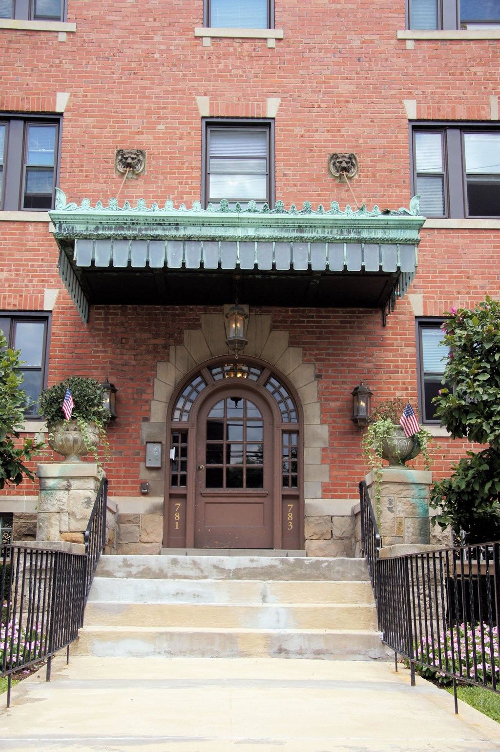 the front of a brick building with a brown door and stairs