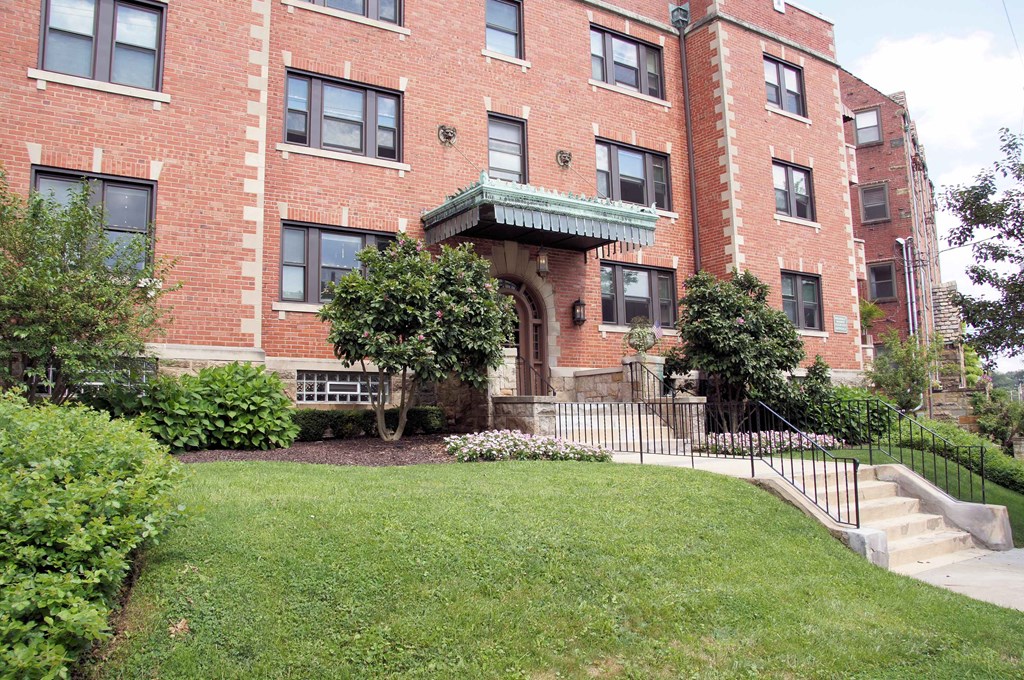 the exterior of a brick apartment building with a yard and stairs