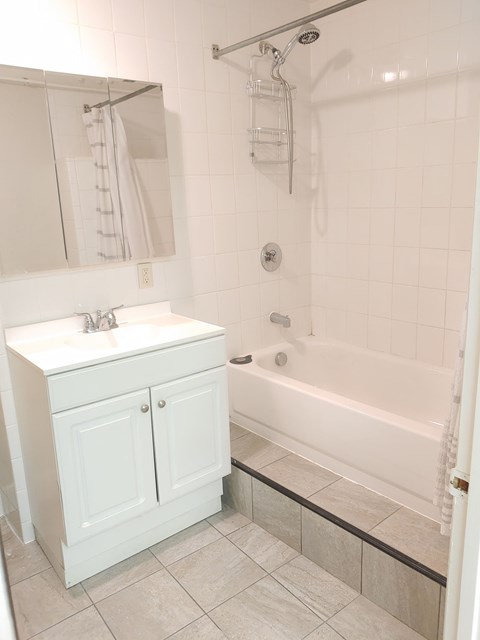 a white bathroom with a sink and a bath tub